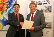 Juni 2012: Landrat Manfred Nahrstedt (r.) überreicht dem neuen Bezirksschornsteinfegermeister Ole Petersen die Bestellungsurkunde.